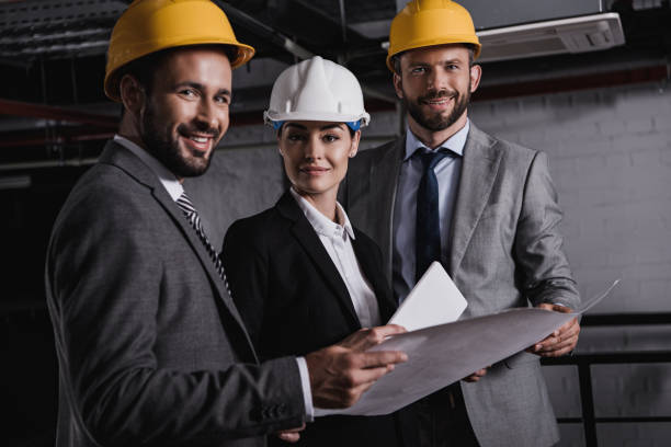 istock architects in suits and helmets working with blueprint and digital tablet on construction together 1011332260