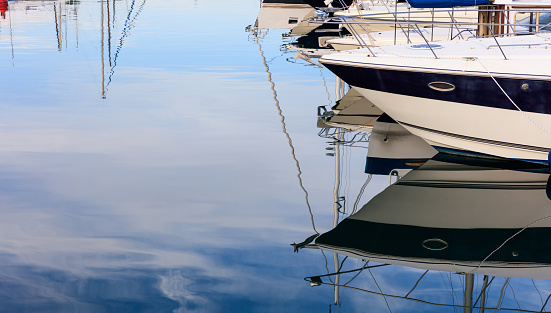 Reflection of boats moored in a marina at Larnaca, Cyprus. Blue sky and sea background.