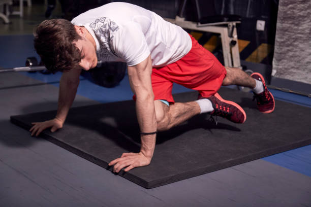 istock one young man, exercise in gym indoors, one leg complicated plank sideways. 1011353798