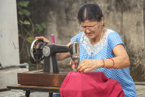 Portrait of senior  women making clothes sitting at sewing machine outdoor
