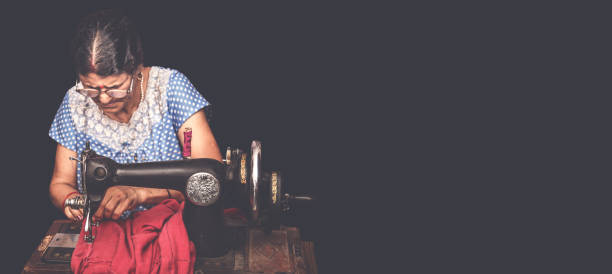 Portrait of senior  women making clothes sitting at sewing machine on the floor of her home