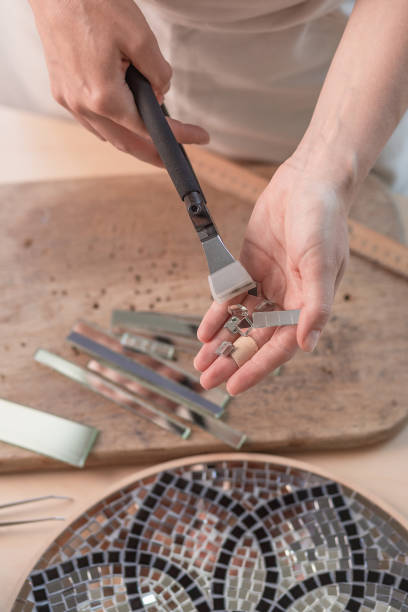 folhas de corte de artista de vitrais em quadrados pequenos de mosaico. close-up - mosaic human hand craft artist - fotografias e filmes do acervo