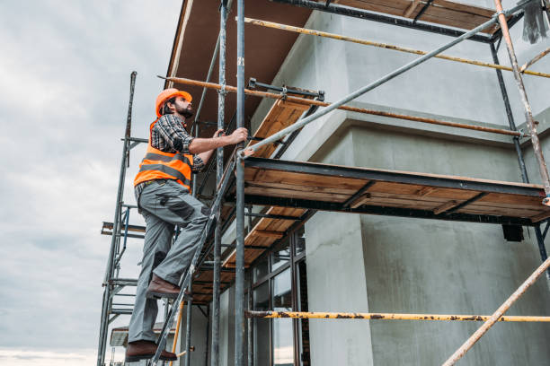 handsome builder climbing on scaffolding at construction site stock photo