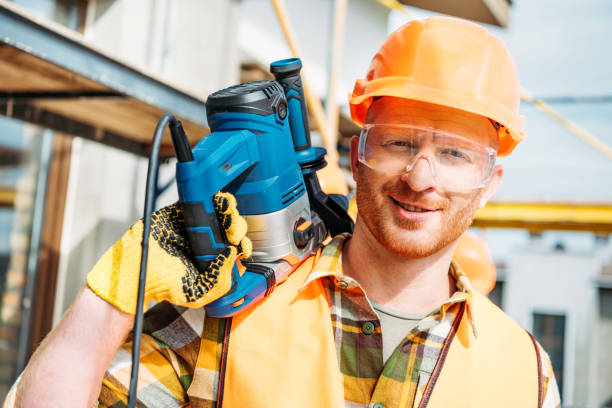 istock handsome smiling builder holding power drill on shoulder and looking at camera 1011361344