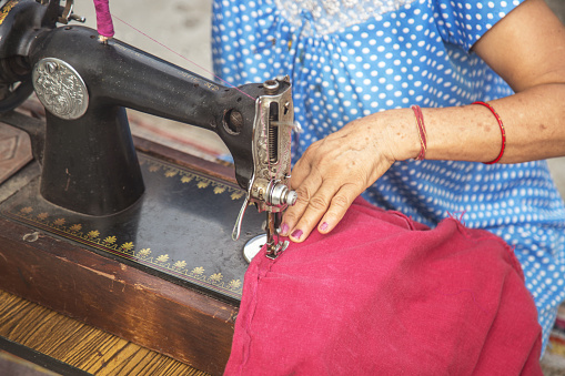 Cropped close up of a woman using sewing machine
