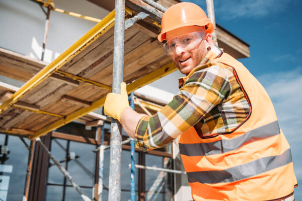 istock handsome builder climbing on scaffolding at construction site and looking at camera 1011361496