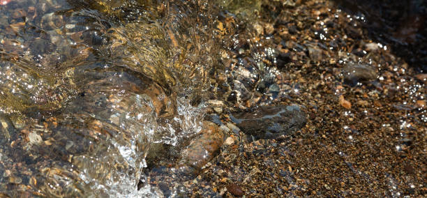istock Water rolling over stones onto sand 1011371558