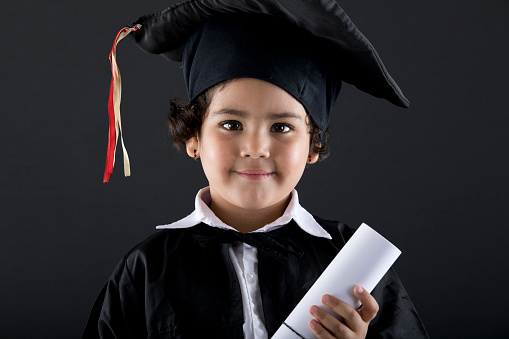 Schoolgirl graduate holding diploma in graduation gown