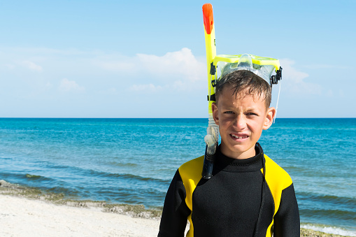 Boy in divingsuit and mask and snorkel at sea background