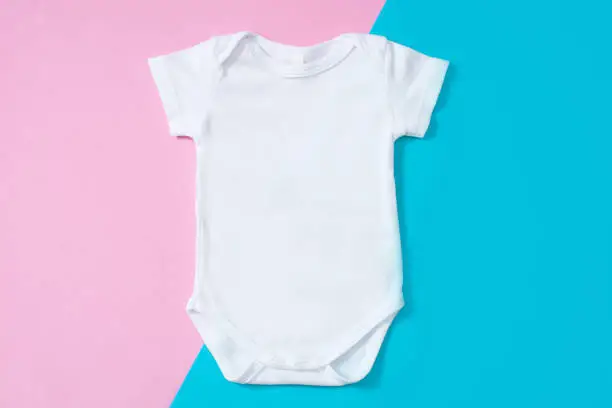 White baby romper on pink and blue background