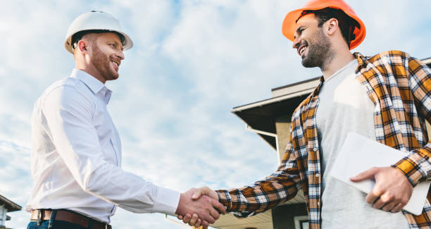 istock bottom view of smiling architects shaking hands in front of construction site 1011404448