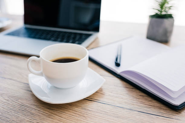 istock close up view of coffee cup, empty textbook and laptop with blank screen on wooden table 1011411376
