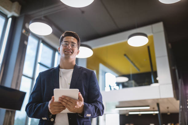 istock Smiling businessman standing in the office holding a digital tablet 1011411766