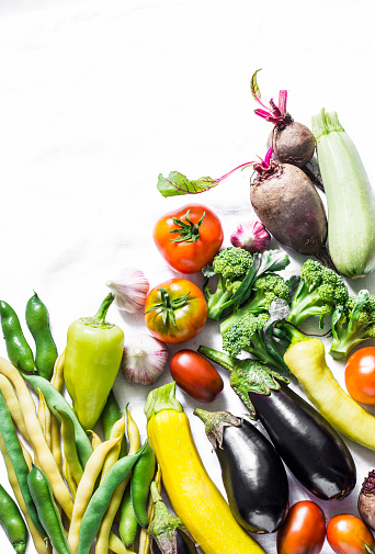 Seasonal organic vegetables background - eggplant, zucchini, pepper, green beans, beet, tomatoes, broccoli on a light background, top view. Flat lay, copy space