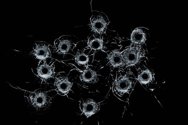 istock Broken glass multiple bullet holes in glass isolated on black 1011416422
