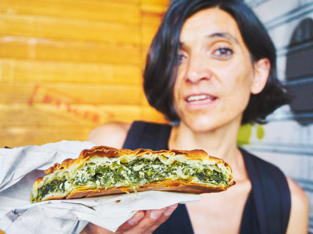 greek woman eating a traditional spanakotiropita, spinach and feta pie. - pie spinach spanakopita filo pastry imagens e fotografias de stock