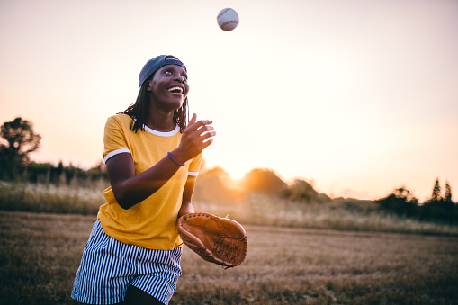 Gorgeous and fashionable black girl playing baseball outdoors in nature.