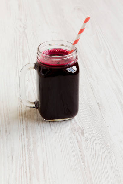 istock Beetroot smoothie in glass jar mug on white wooden background, side view. 1011467334