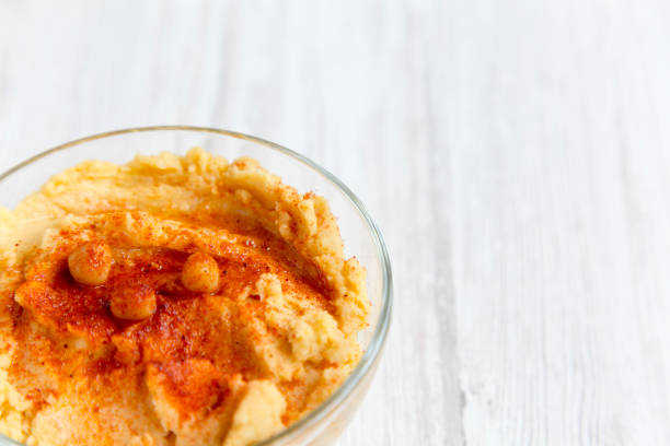 Bowl of Hummus with spices on a white wooden surface, low angle. Close-up. Copy space.