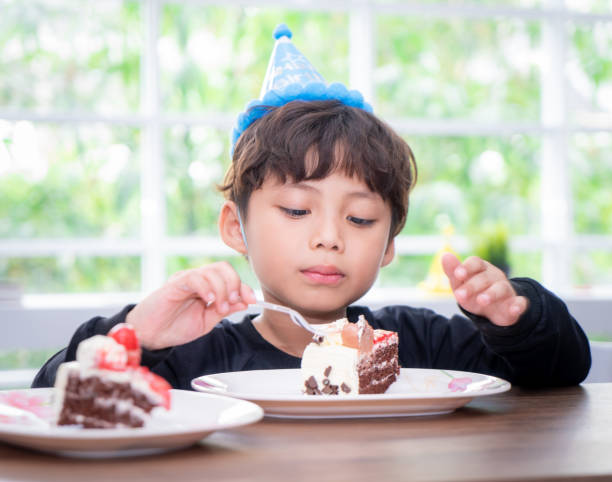 istock Kid with party hat is eating birthday cake 1011473734