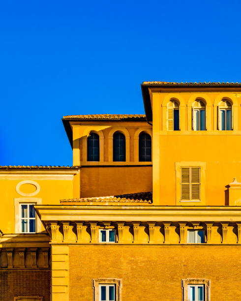 Exterior facade of typical roman palazzo style with orange colors against blue sky background
