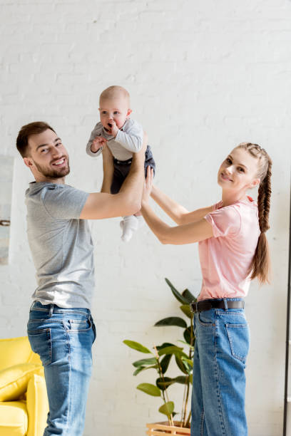 istock happy parents playing with little son at home 1011493788