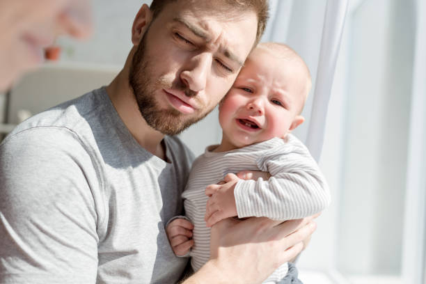 istock young father holding crying little son 1011494044