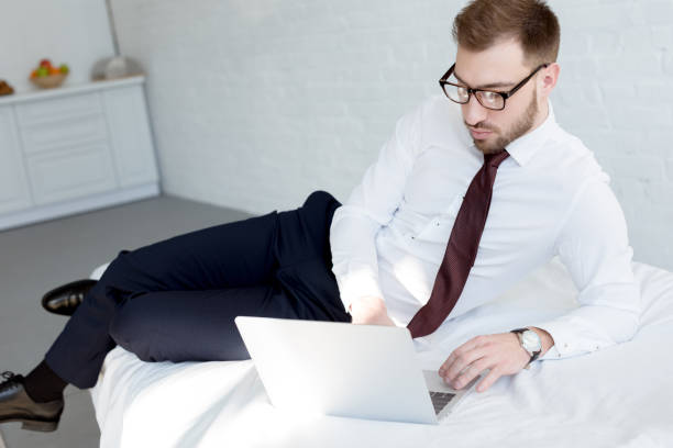 istock businessman in eyeglasses using laptop in bedroom 1011502198