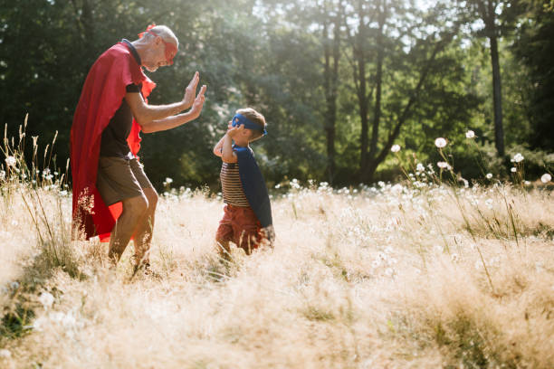 istock Grandfather Dressed As Superhero Plays Outside With Grandson 1011514528
