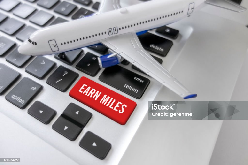 Earn miles Miniature plane on a laptop with a “Earn miles”button Commercial Airplane Stock Photo
