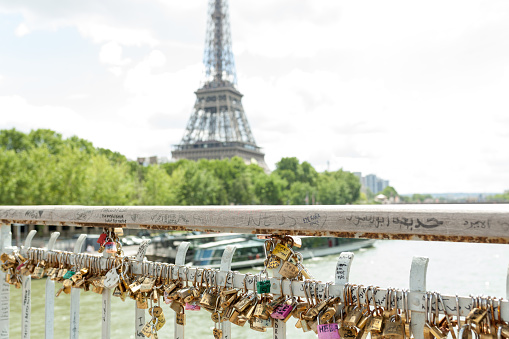Paris, France, Europe - June 02, 2018: Padlocks on the Arts Bridge over the Seine River in Paris With Eifel tower on the background.