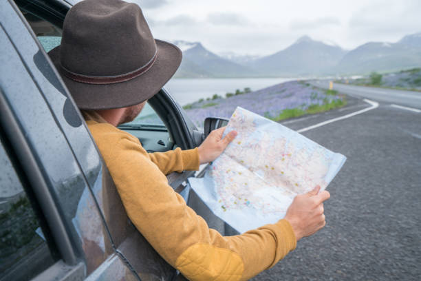 istock Young man in car looking at map, road trip concept vacations 1011553828