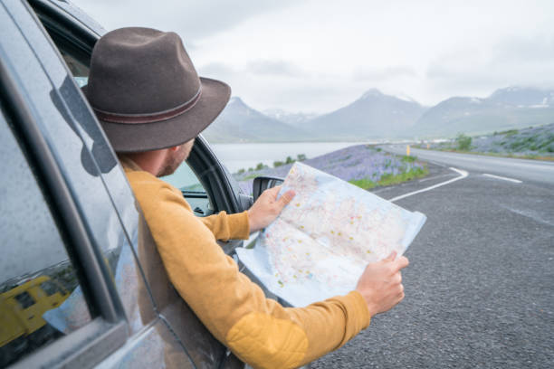 istock Young man in car looking at map, road trip concept vacations 1011553834