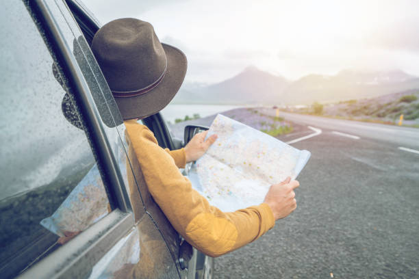 istock Young man in car looking at map, road trip concept vacations 1011554908