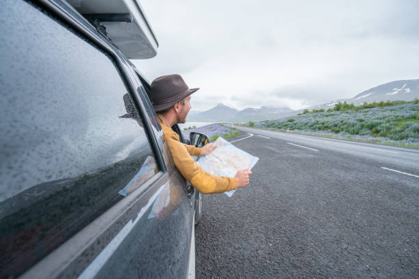 istock Young man in car looking at map, road trip concept vacations 1011555960