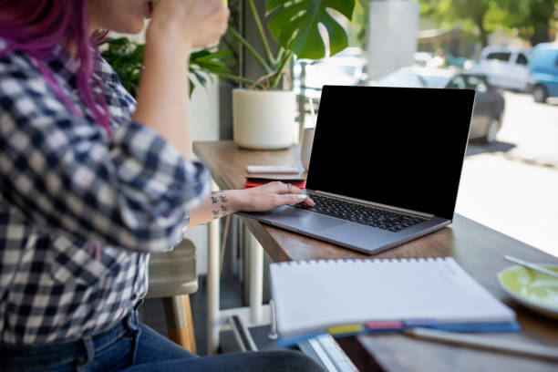 istock Woman typing on notebook with blank screen with copy space for your text or advertising content, sitting at wooden table 1011567292