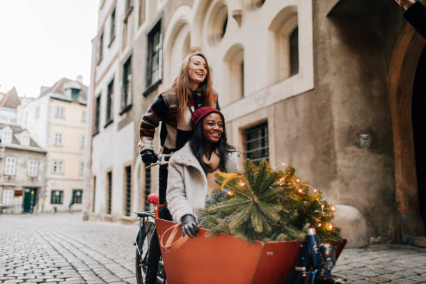 Taking our Christmas tree home Two girlfriends have chosen their Christmas tree and ride it on a cargo bike cargo bike photos stock pictures, royalty-free photos & images