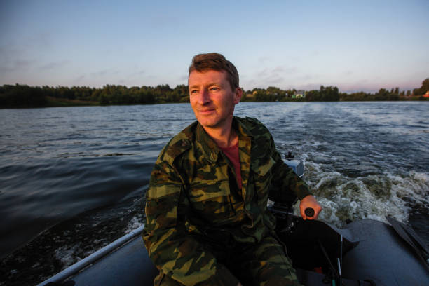 istock A man in camouflage controls a motor boat on the lake. 1011569822