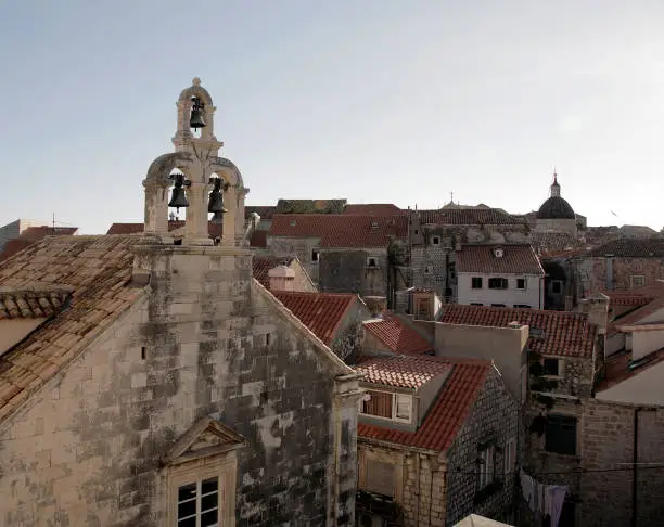 A view of a trio of church bells and red tile roofs in Dubrovnik, Croatia.