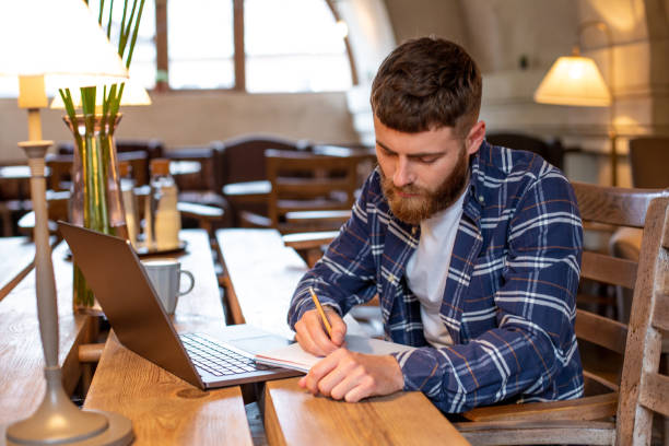 istock Casual business man or freelancer planning his work on notebook, working on laptop computer with smart phone, cup of coffee on table at coffee shop or home office 1011570146