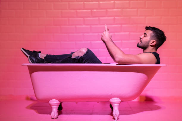 istock Man Using Mobile in the pink bathtube 1011574698