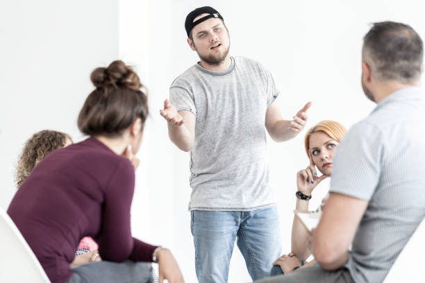 istock Difficult young man talking about youth problems during group therapy with psychologist 1011590386