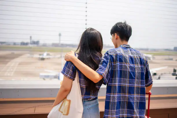Young Asian couple looking at airplanes at airport observation deck