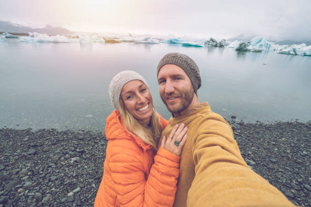 istock Young couple taking selfie with glacier lagoon, icebergs floating on water 1011598368