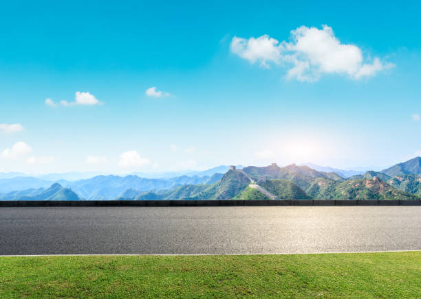 istock Asphalt road and great wall with mountains under the blue sky 1011616270