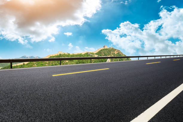 istock Asphalt road and great wall with mountains under the blue sky 1011616528