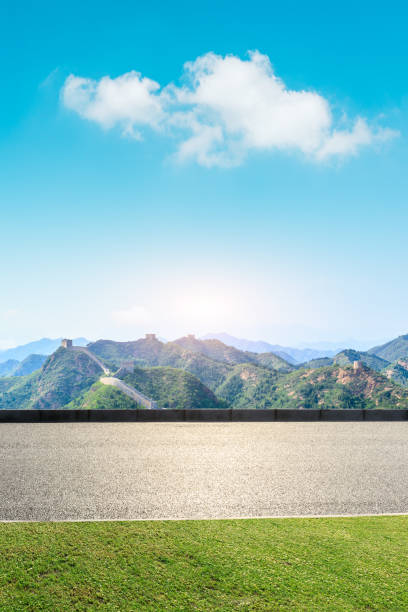 istock Asphalt road and great wall with mountains under the blue sky 1011619232