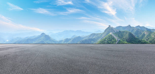 istock Asphalt road and great wall with mountains under the blue sky 1011619238
