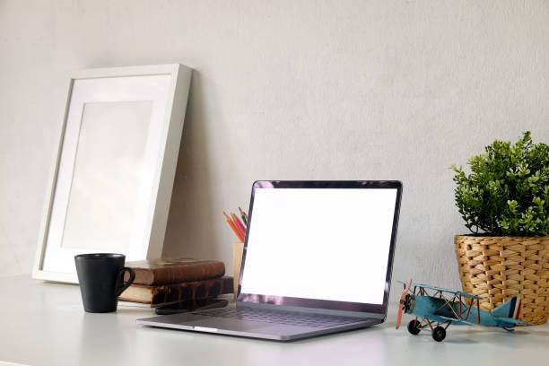 istock Stylish workspace with laptop and mockup poster on white wooden desk. 1011626310