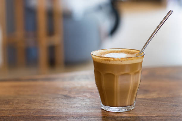 café au lait, macchiato sur un verre transparent avec une cuillère à l’intérieur. - latte machiatto photos et images de collection